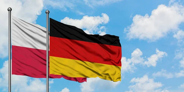 Polen und Deutschland wehen gemeinsam im Wind vor dem wolkenverhangenen blauen Himmel. Diplomatie-Konzept, internationale Beziehungen. — Stockfoto