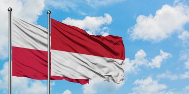 Polonya ve Monako bayrağı birlikte beyaz bulutlu mavi gökyüzüne karşı rüzgarda sallayarak. Diplomasi kavramı, uluslararası ilişkiler.