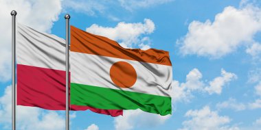 Polonya ve Nijer bayrağı birlikte beyaz bulutlu mavi gökyüzüne karşı rüzgarda sallayarak. Diplomasi kavramı, uluslararası ilişkiler.