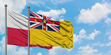 Polonya ve Niue bayrağı birlikte beyaz bulutlu mavi gökyüzüne karşı rüzgarda sallayarak. Diplomasi kavramı, uluslararası ilişkiler.