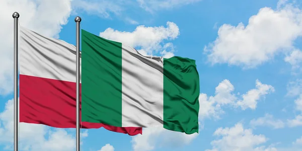 Bandera de Polonia y Nigeria ondeando en el viento contra el cielo azul nublado blanco juntos. Concepto diplomático, relaciones internacionales . — Foto de Stock