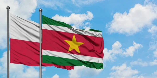 Bandera de Polonia y Surinam ondeando en el viento contra el cielo azul nublado blanco juntos. Concepto diplomático, relaciones internacionales . — Foto de Stock