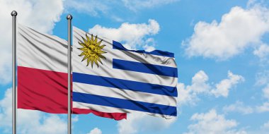 Polonya ve Uruguay bayrağı birlikte beyaz bulutlu mavi gökyüzüne karşı rüzgarda sallayarak. Diplomasi kavramı, uluslararası ilişkiler.