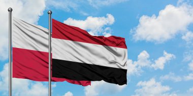 Polonya ve Yemen bayrağı birlikte beyaz bulutlu mavi gökyüzüne karşı rüzgarda sallayarak. Diplomasi kavramı, uluslararası ilişkiler.
