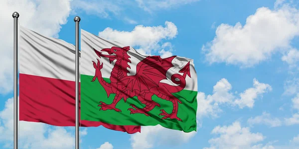 A bandeira da Polônia e do País de Gales agitando no vento contra o céu azul nublado branco juntos. Conceito de diplomacia, relações internacionais . — Fotografia de Stock