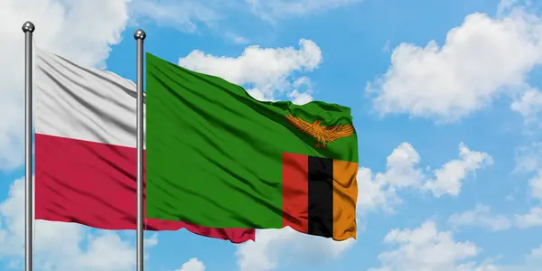 Bandera de Polonia y Zambia ondeando en el viento contra el cielo azul nublado blanco juntos. Concepto diplomático, relaciones internacionales . — Foto de Stock