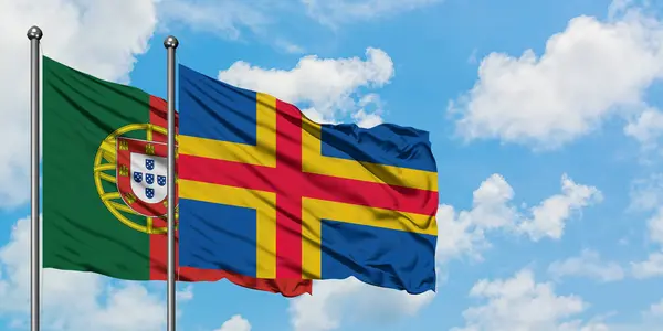 Portugal och Åland flagga vifta i vinden mot vit grumlig blå himmel tillsammans. Diplomatisk koncept, internationella relationer. — Stockfoto