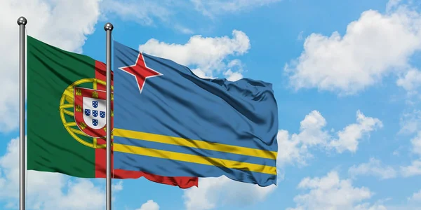 Portugal en Aruba vlag zwaaien in de wind tegen witte bewolkte blauwe hemel samen. Diplomatie concept, internationale betrekkingen. — Stockfoto