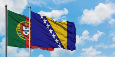 Portekiz ve Bosna Hersek bayrağı birlikte beyaz bulutlu mavi gökyüzüne karşı rüzgarda sallayarak. Diplomasi kavramı, uluslararası ilişkiler.
