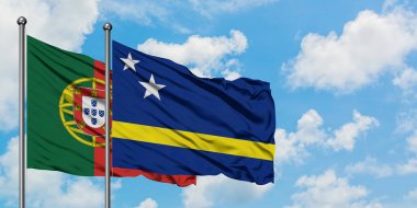 Portekiz ve Curacao bayrağı birlikte beyaz bulutlu mavi gökyüzüne karşı rüzgarda sallayarak. Diplomasi kavramı, uluslararası ilişkiler.