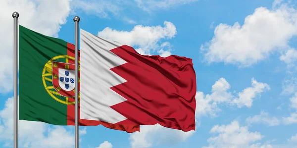 Portugalsko a Bahrašin vlajky ve větru mávali proti bíle zatažené modré obloze. Diplomacie, mezinárodní vztahy. — Stock fotografie