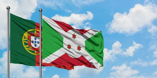 Bandera de Portugal y Burundi ondeando en el viento contra el cielo azul nublado blanco juntos. Concepto diplomático, relaciones internacionales . — Foto de Stock