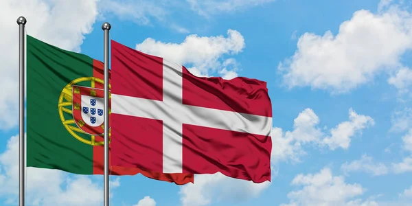 Португалия и Дания вместе машут флагом на ветру против белого облачного голубого неба. Концепция дипломатии, международные отношения . — стоковое фото