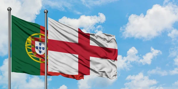 一緒に白い曇り青い空に対して風に手を振るポルトガルとイングランドの旗。外交概念、国際関係. — ストック写真