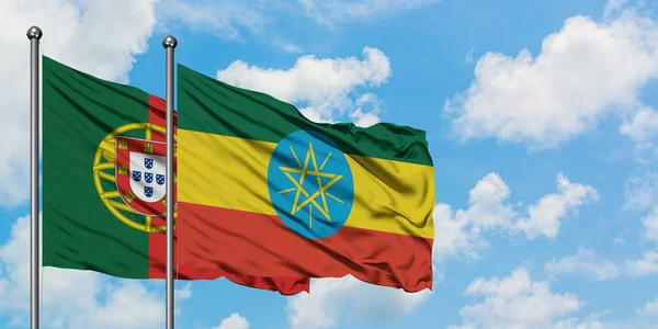 Bandera de Portugal y Etiopía ondeando en el viento contra el cielo azul nublado blanco juntos. Concepto diplomático, relaciones internacionales . —  Fotos de Stock