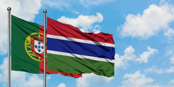 Bandera de Portugal y Gambia ondeando en el viento contra el cielo azul nublado blanco juntos. Concepto diplomático, relaciones internacionales . — Foto de Stock