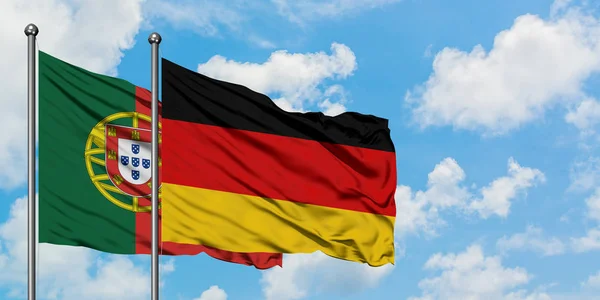 Bandera de Portugal y Alemania ondeando en el viento contra el cielo azul nublado blanco juntos. Concepto diplomático, relaciones internacionales . — Foto de Stock