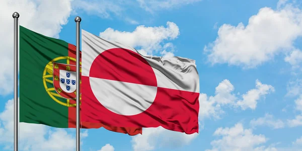 Portugal och Grönland sjunker vifta i vinden mot vit grumlig blå himmel tillsammans. Diplomatisk koncept, internationella relationer. — Stockfoto