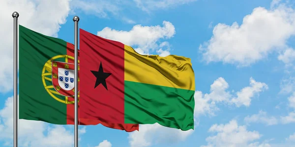 Le Portugal et la Guinée Drapeau de Bissau agitant dans le vent contre ciel bleu nuageux blanc ensemble. Concept de diplomatie, relations internationales . — Photo