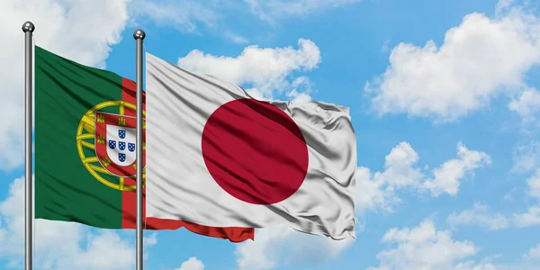Portugália és Japán zászló integetett a szél ellen, fehér felhős kék ég együtt. Diplomáciai koncepció, nemzetközi kapcsolatok. — Stock Fotó