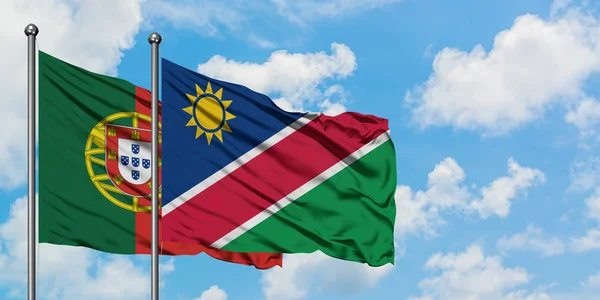 Portugal en Namibië vlag zwaaien in de wind tegen witte bewolkte blauwe hemel samen. Diplomatie concept, internationale betrekkingen. — Stockfoto