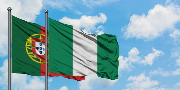 Bandera de Portugal y Nigeria ondeando en el viento contra el cielo azul nublado blanco juntos. Concepto diplomático, relaciones internacionales . — Foto de Stock