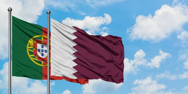 Bandera de Portugal y Qatar ondeando en el viento contra el cielo azul nublado blanco juntos. Concepto diplomático, relaciones internacionales . — Foto de Stock