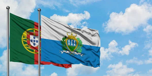 Bandera de Portugal y San Marino ondeando en el viento contra el cielo azul nublado blanco juntos. Concepto diplomático, relaciones internacionales . — Foto de Stock