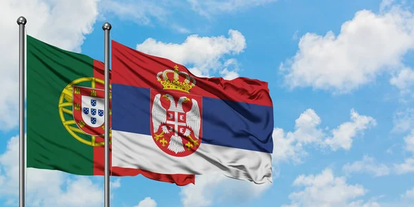 Bandera de Portugal y Serbia ondeando en el viento contra el cielo azul nublado blanco juntos. Concepto diplomático, relaciones internacionales . — Foto de Stock