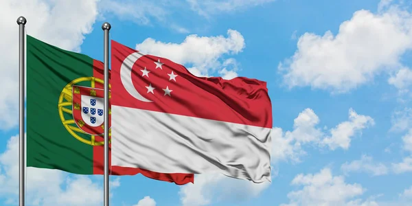 Portogallo e Singapore sventolano bandiera nel vento contro bianco cielo blu nuvoloso insieme. Concetto di diplomazia, relazioni internazionali . — Foto Stock