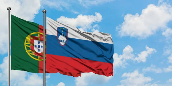 Portugal and Slovenia flag waving in the wind against white cloudy blue sky together. Diplomacy concept, international relations.
