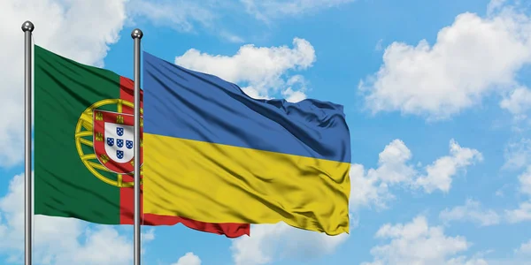 Bandera de Portugal y Ucrania ondeando en el viento contra el cielo azul nublado blanco juntos. Concepto diplomático, relaciones internacionales . — Foto de Stock