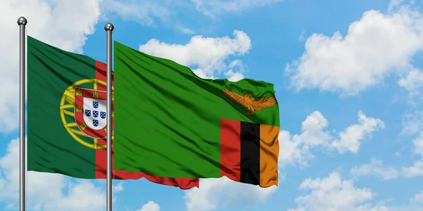 Portugal och Zambia flagga viftande i vinden mot vit grumlig blå himmel tillsammans. Diplomatisk koncept, internationella relationer. — Stockfoto