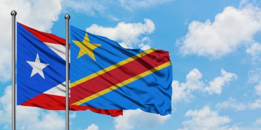 Porto Riko ve Kongo bayrağı birlikte beyaz bulutlu mavi gökyüzüne karşı rüzgarda sallayarak. Diplomasi kavramı, uluslararası ilişkiler.