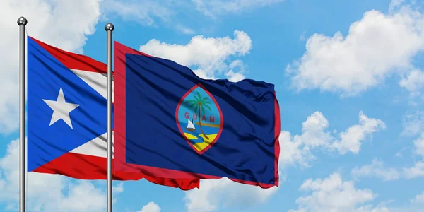 Porto Riko ve Guam bayrağı birlikte beyaz bulutlu mavi gökyüzüne karşı rüzgarda sallayarak. Diplomasi kavramı, uluslararası ilişkiler. — Stok fotoğraf