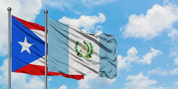 Porto Riko ve Guatemala bayrağı birlikte beyaz bulutlu mavi gökyüzüne karşı rüzgarda sallayarak. Diplomasi kavramı, uluslararası ilişkiler. — Stok fotoğraf