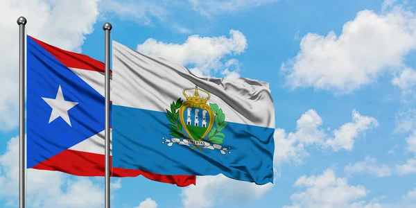 Puerto Rico and San Marino flag waving in the wind against white cloudy blue sky together. Diplomacy concept, international relations. — Stock Photo, Image