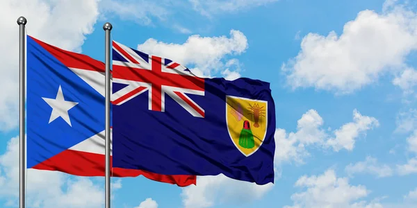 波多黎各和特克斯和凯科斯群岛国旗在风中飘扬，与白云蓝天相拥。外交概念、国际关系. — 图库照片