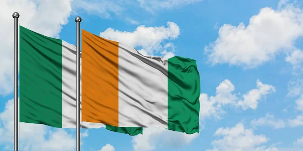 Nigeria och Elfenbenskusten flagga viftande i vinden mot vit grumlig blå himmel tillsammans. Diplomatisk koncept, internationella relationer. — Stockfoto