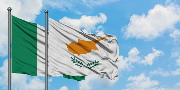 Bandera de Nigeria y Chipre ondeando en el viento contra el cielo azul nublado blanco juntos. Concepto diplomático, relaciones internacionales . — Foto de Stock
