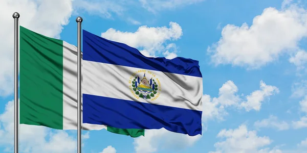 Bandera de Nigeria y El Salvador ondeando en el viento contra el cielo azul nublado blanco juntos. Concepto diplomático, relaciones internacionales . —  Fotos de Stock