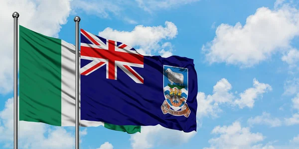 Bandera de Nigeria e Islas Malvinas ondeando en el viento contra el cielo azul nublado blanco juntos. Concepto diplomático, relaciones internacionales . — Foto de Stock