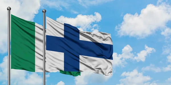 Флаг Нигерии и Финляндии, размахивающий на ветру против белого облачного голубого неба. Концепция дипломатии, международные отношения . — стоковое фото