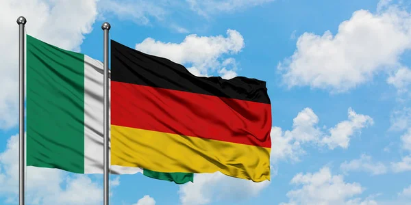 Bandera de Nigeria y Alemania ondeando en el viento contra el cielo azul nublado blanco juntos. Concepto diplomático, relaciones internacionales . — Foto de Stock