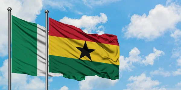 Bandera de Nigeria y Ghana ondeando en el viento contra el cielo azul nublado blanco juntos. Concepto diplomático, relaciones internacionales . — Foto de Stock