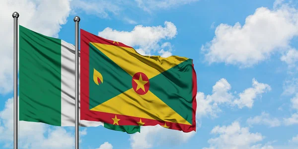 Bandera de Nigeria y Granada ondeando en el viento contra el cielo azul nublado blanco juntos. Concepto diplomático, relaciones internacionales . — Foto de Stock