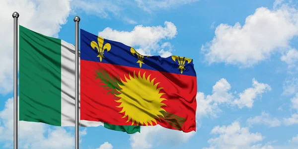 Bandera de Nigeria y Guadalupe ondeando en el viento contra el cielo azul nublado blanco juntos. Concepto diplomático, relaciones internacionales . — Foto de Stock