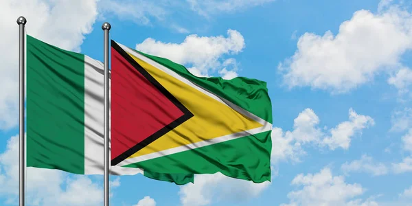 Nigeria e Guyana sventolano nel vento contro il bianco cielo blu nuvoloso insieme. Concetto di diplomazia, relazioni internazionali . — Foto Stock