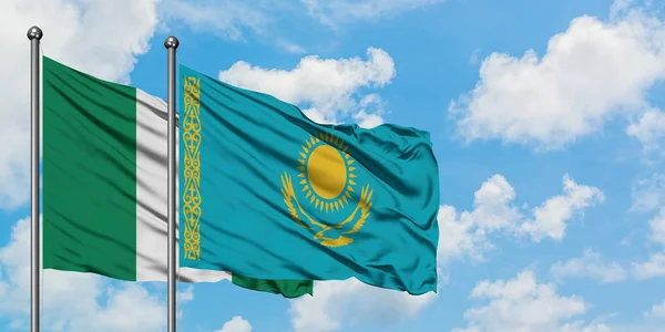 Bandera de Nigeria y Kazajstán ondeando en el viento contra el cielo azul nublado blanco juntos. Concepto diplomático, relaciones internacionales . — Foto de Stock
