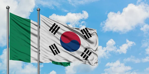 Nigeria i Korea Południowa flaga machając w wiatr przed białym zachmurzone błękitne niebo razem. Koncepcja dyplomacji, stosunki międzynarodowe. — Zdjęcie stockowe